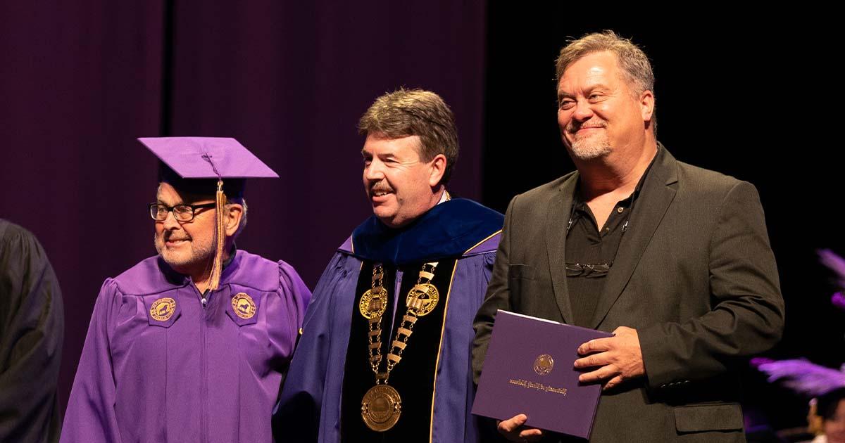 肯·基茨总统与杰伊·约翰逊合影, 已故吉米·约翰逊的儿子, 和大卫·胡德在2021年秋季毕业典礼上.